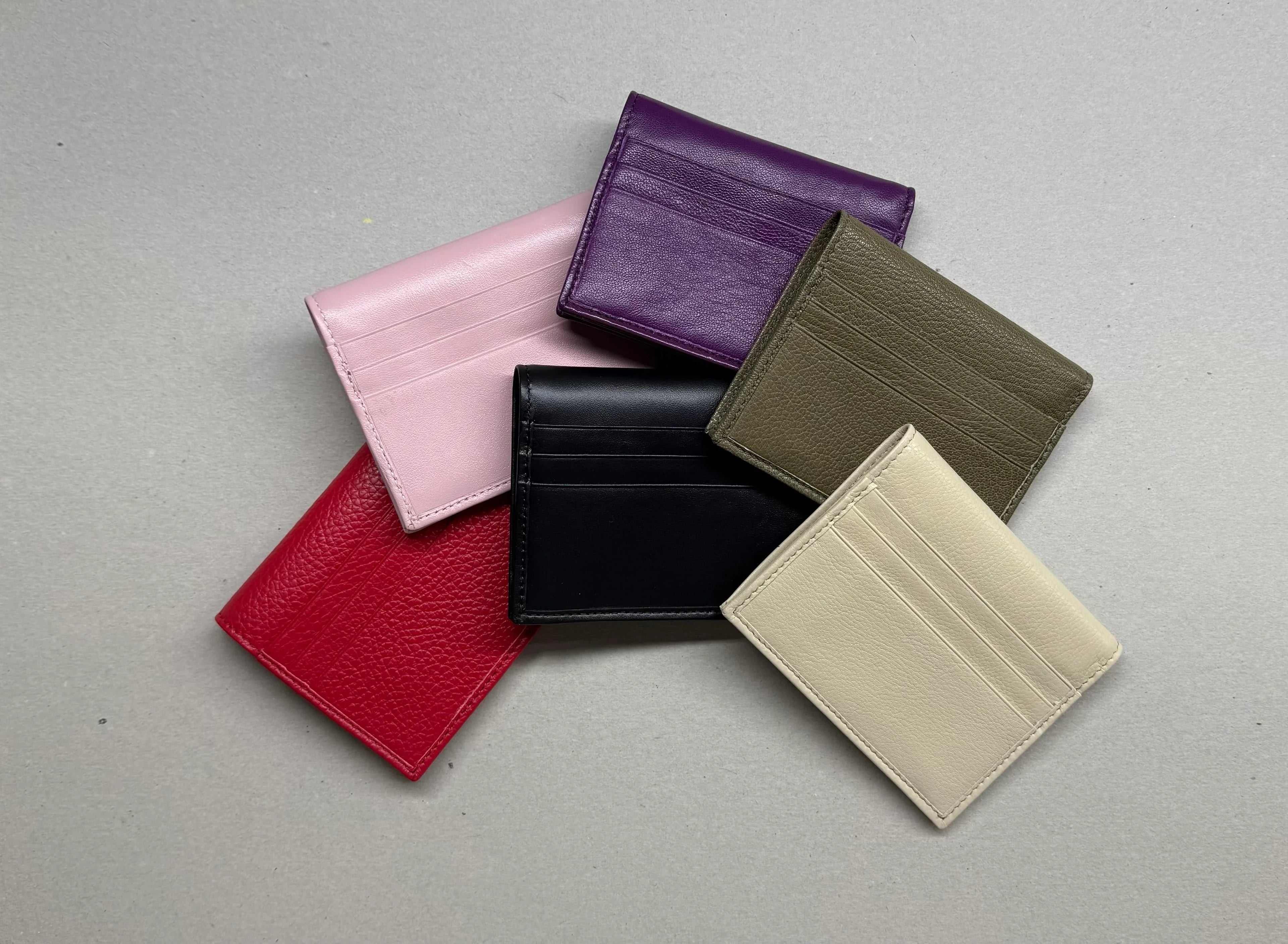 Portacarte in pelle multicolore per donna e uomo, eleganti accessori su sfondo grigio