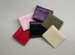 Portacarte in pelle multicolore per donna e uomo, eleganti accessori su sfondo grigio